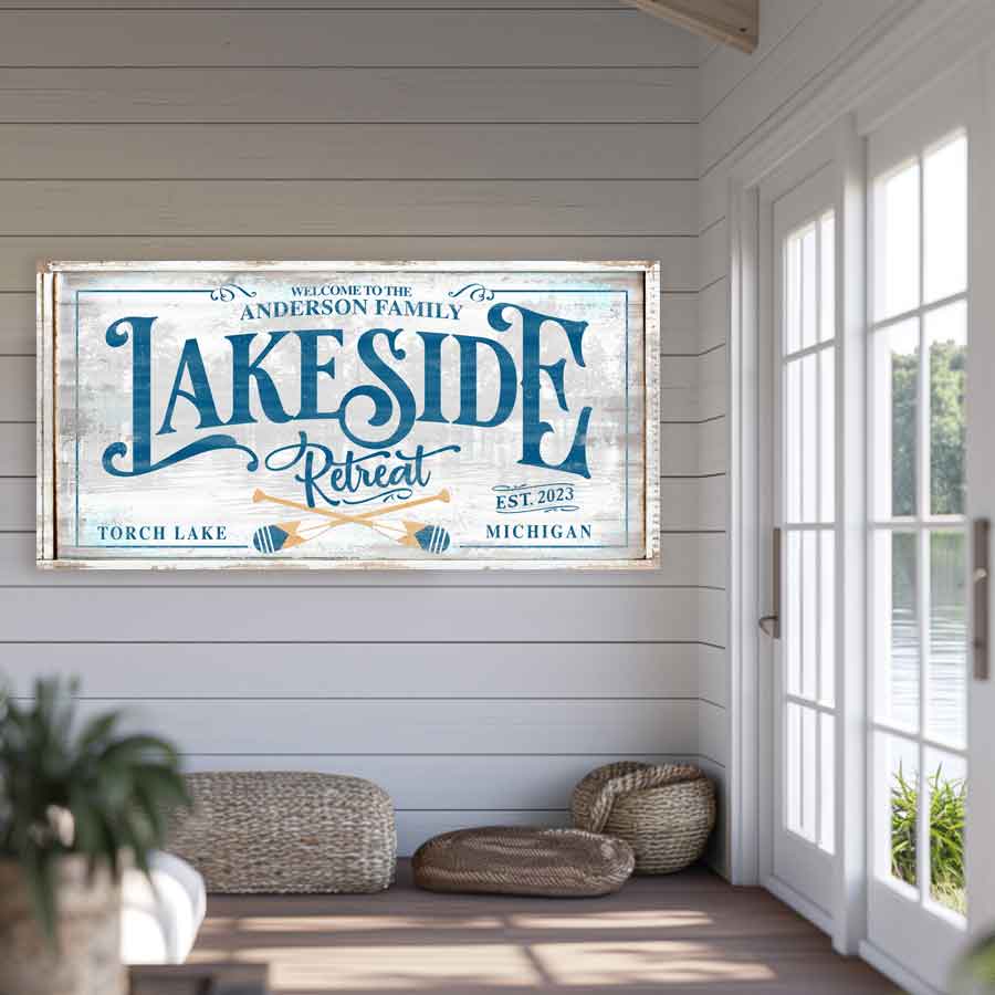 lake house sign on faux distressed wood with blue letters that say Lakeside Retreat with paddles.