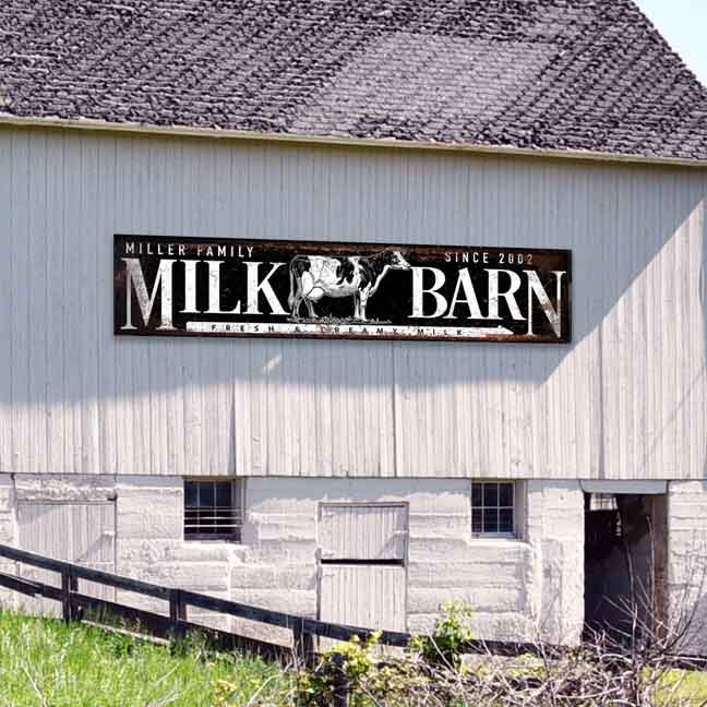 Large metal barn sign that say Milk Barn with family name on rusty black background