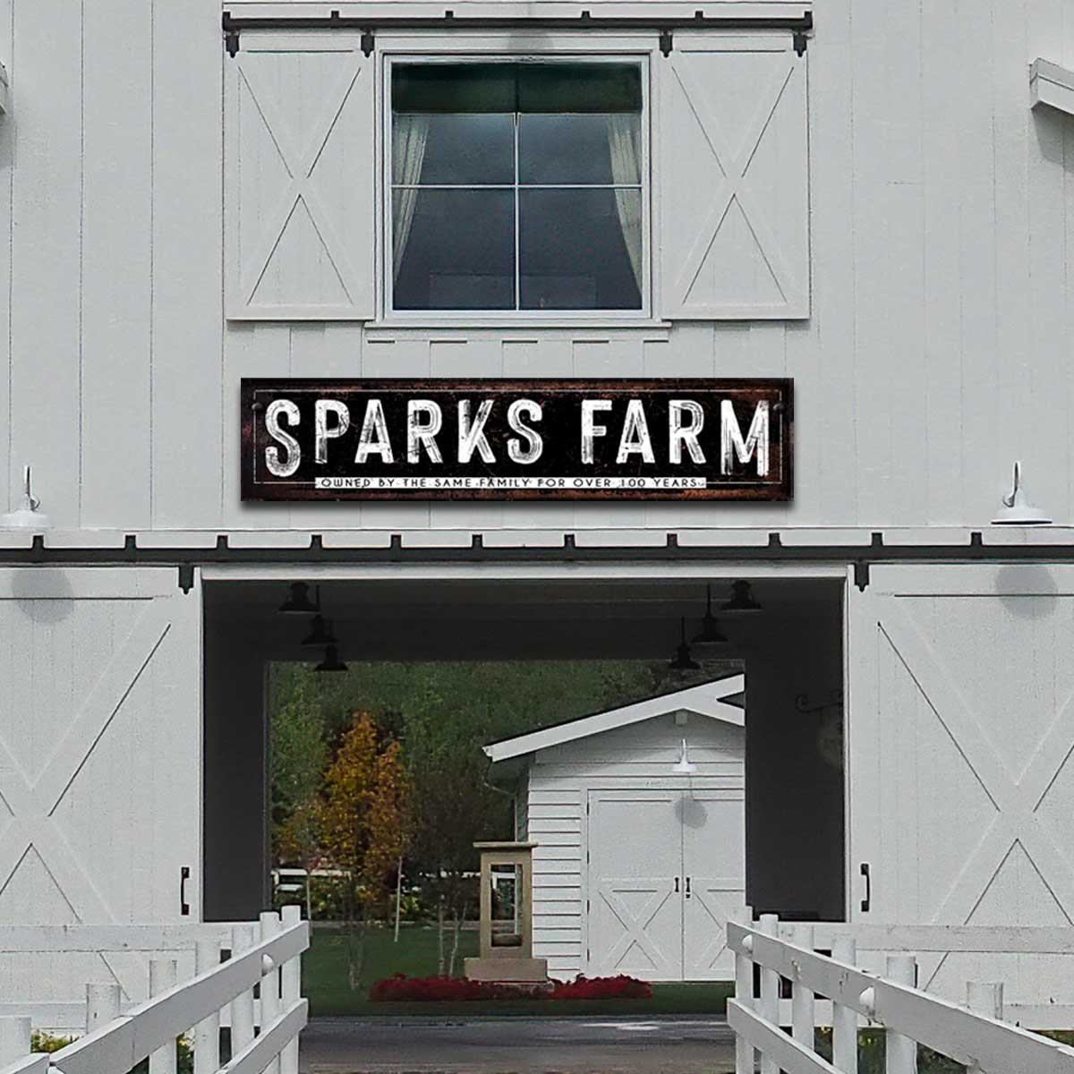 metal sign for a barn in black and white on the side of a white barn