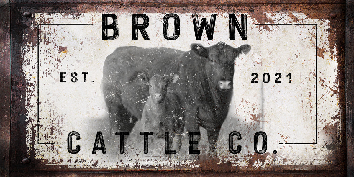 Cattle Ranch Sign with Red Angus cows standing in front. Words Brown Cattle Company, with establish date on distressed rusty frame and white peeled paint cow print.