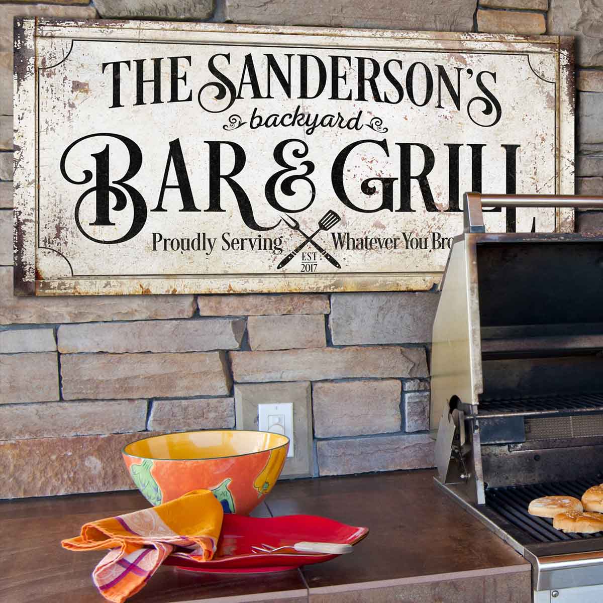 Backyard Bar and Grill Sign with distressed faux fram and the words [family name] Backyard Bar and Grill, proudly serving whatever you brought.