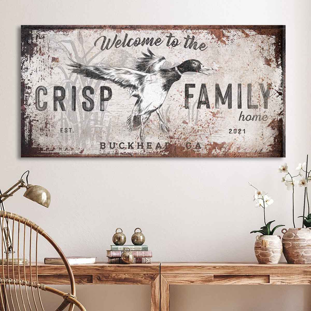 Duck Hunting Decor Sign printed on rusted background with white paint and mallard duck flying out of the reeds. With the words [Welcome to the "family" home, est. 2021 with city and state. Black & white illustration