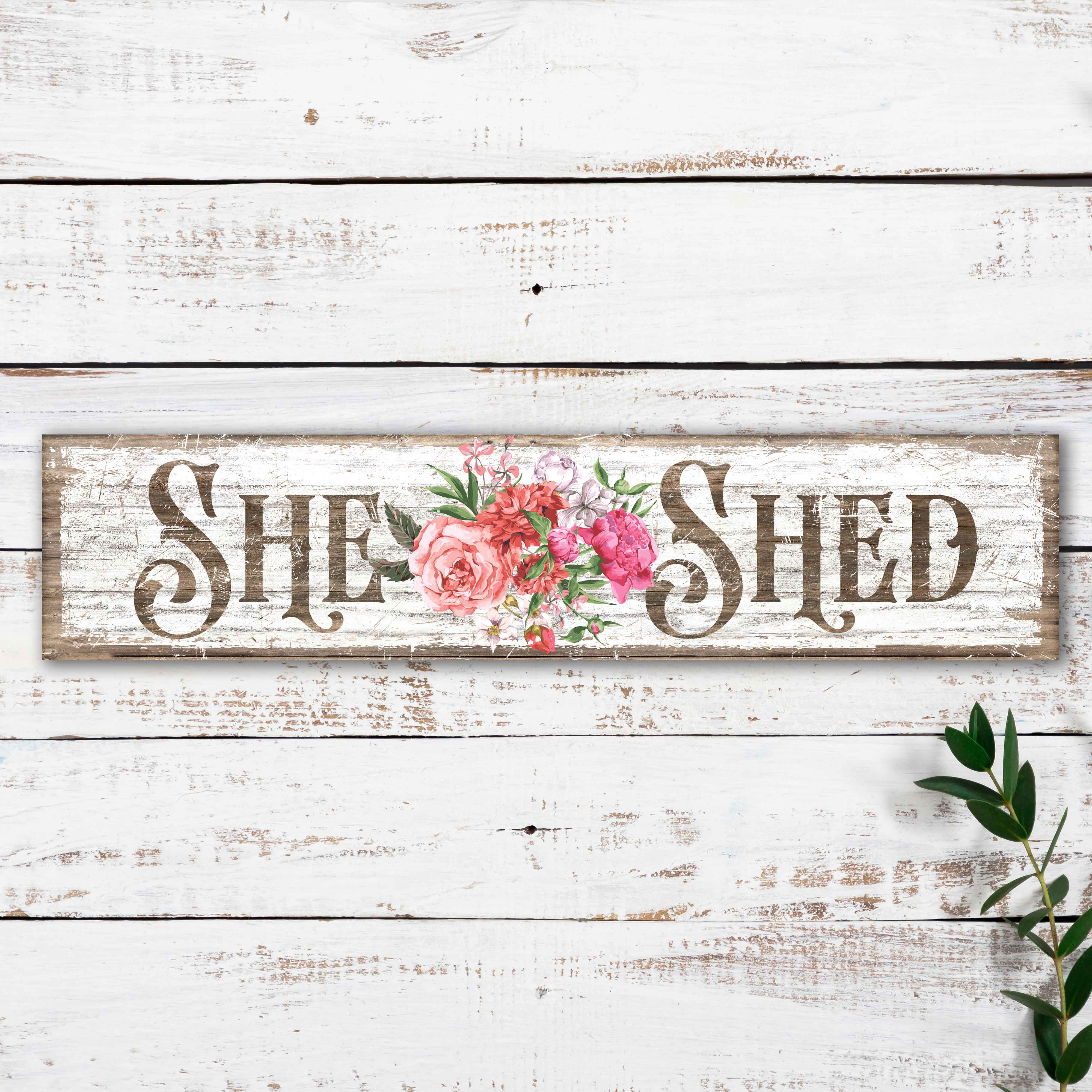 white faux distressed sign with "She Shed" and a bouquet of flowers.