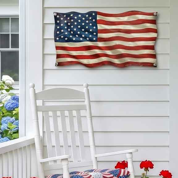 American flag hanging on a white wall next to a white rocking chair with a patriotic cushion.