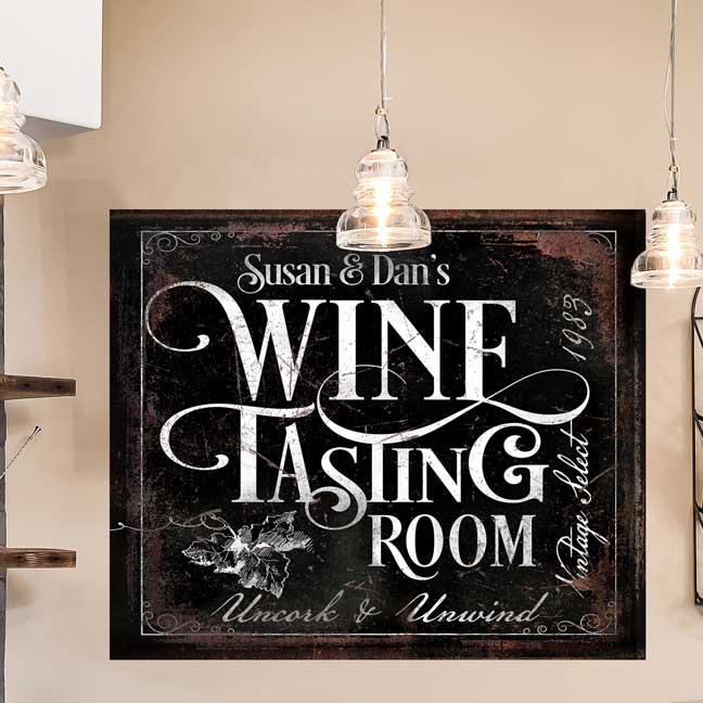 Wine Tasting Bar Sign on distressed black canvas, with [family name] and the words Wine Tasting Room right next to the wall wine rack