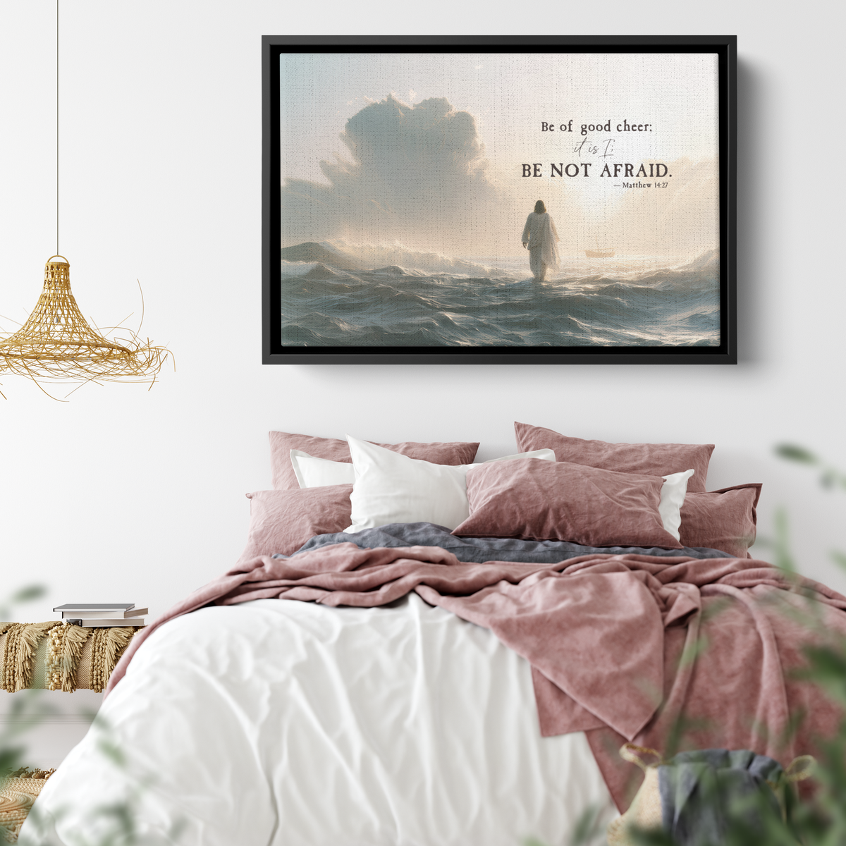 Large Be Not Afraid canvas in a black frame hung above a bed with dusty pink bedding and a rattan pendant light