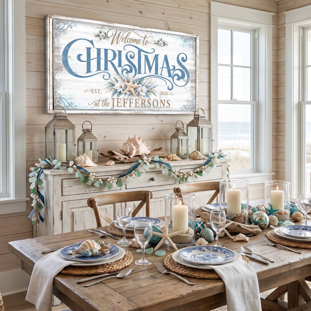 Beach Christmas sign above a whitewashed sideboard in a coastal dining room set with shells, candles and lanterns