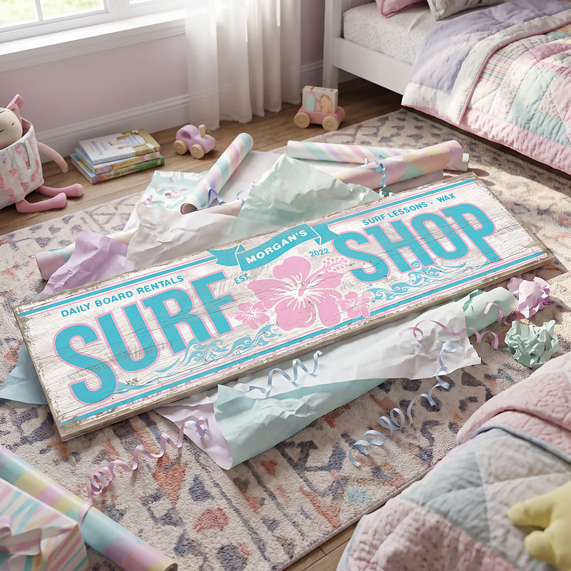 Beach decor surf shop sign laid out with gift wrap and ribbon as a present for a surfer girl