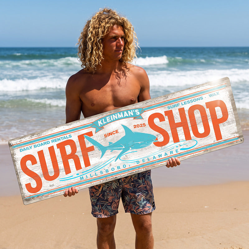 Beach house sign with surf decor carried along the shoreline, showing the full length of the sign