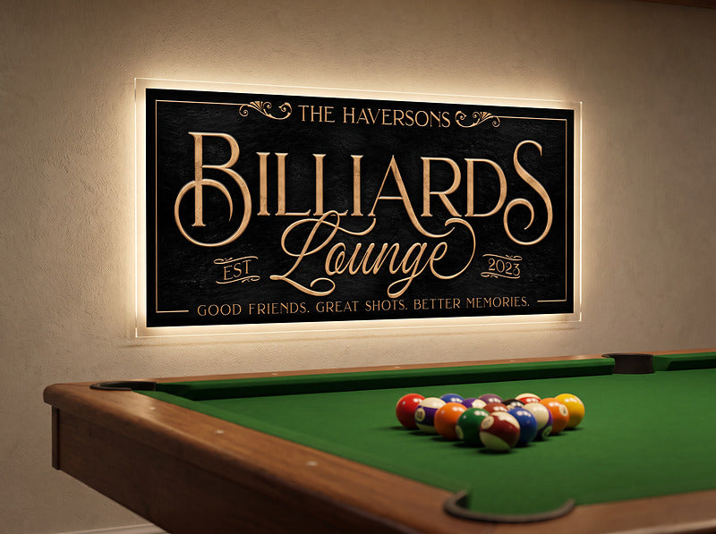 Billiard room decor sign in antique gold lettering on a cream wall above a pool table with racked balls, lighting added by the owner