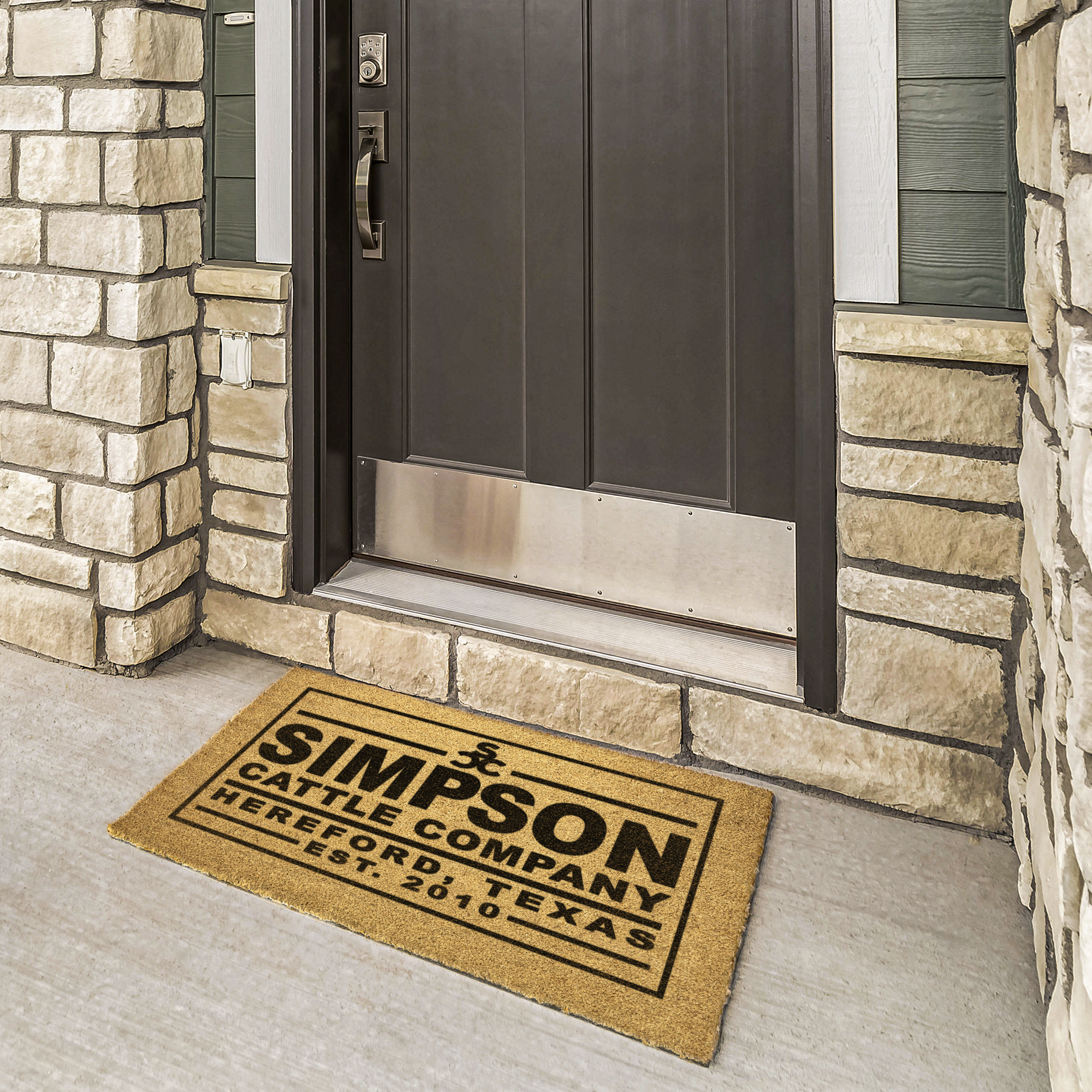 Cattle ranch coir welcome mat with ranch name at a bronze door framed by cream stone