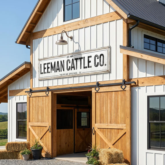 Barn-style building with 'Leeman Cattle Co.' cattle ranch sign on a clear day