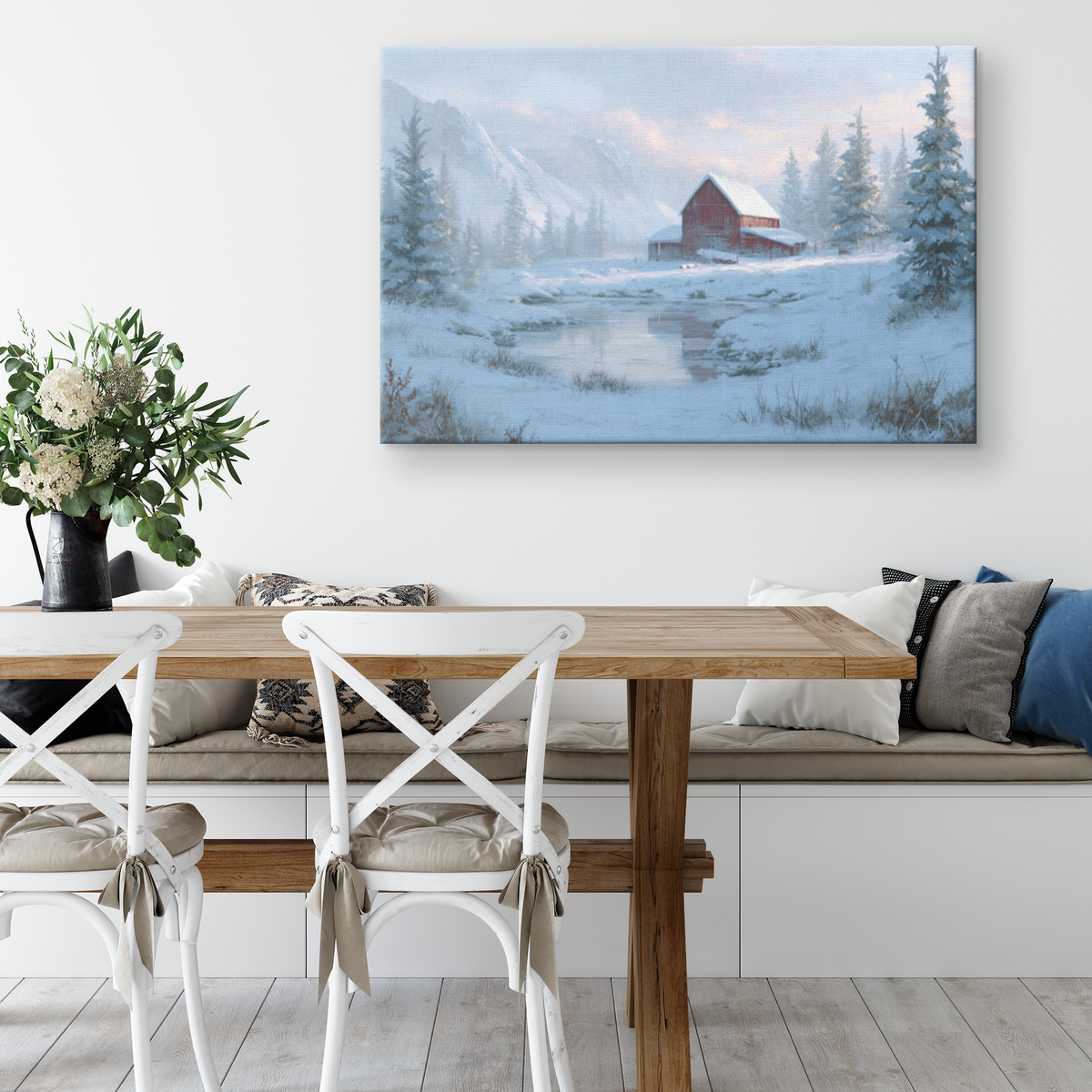 Mountain red barn Christmas canvas above a cushioned dining bench with a white table and cross back chairs
