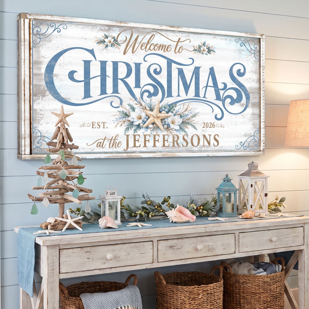 Coastal Christmas welcome sign above a console with a driftwood tree, lanterns and shells