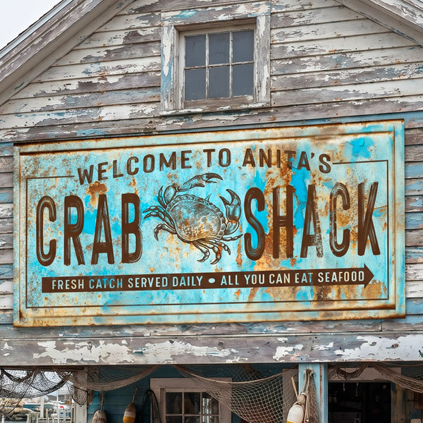 A rustic coastal crab sign 'WELCOME TO ANITA'S CRAB SHACK' with a crab illustration, mounted on a weathered wooden building with peeling blue and white paint.