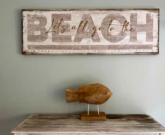 coastal decor beach sign with the words Let's all go to the beach on it.