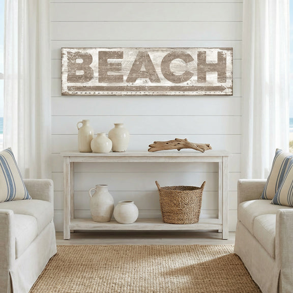 coastal decor living room with 'BEACH' sign on wall, white furniture, and decorative items.