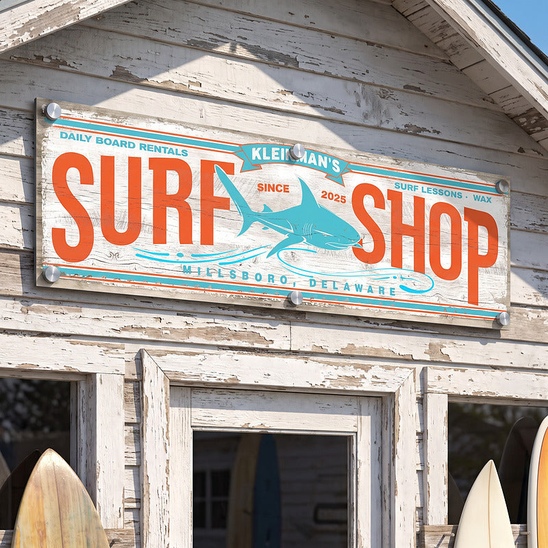 Coastal metal wall art surf sign mounted outdoors above the door of a weathered beach building