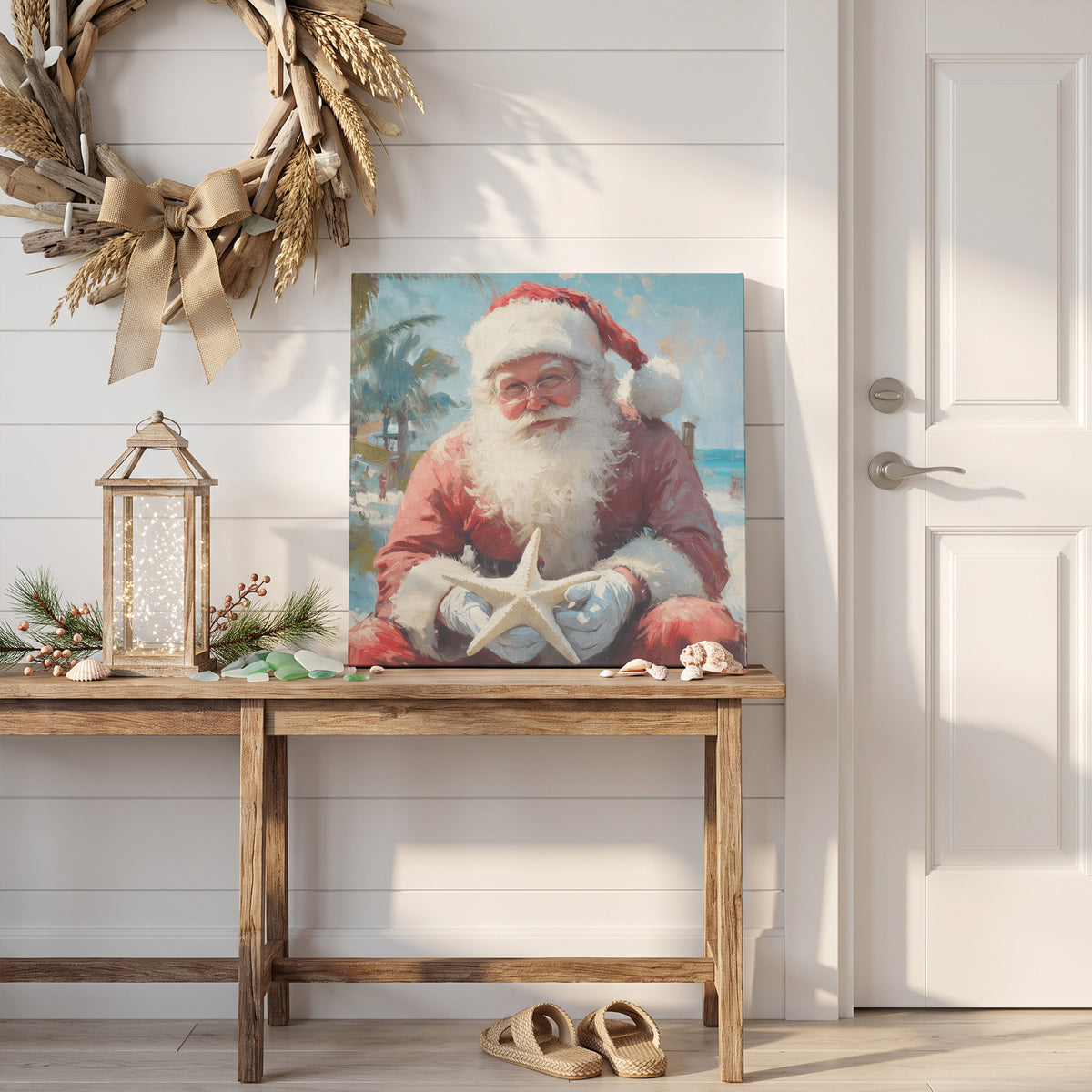 Coastal Santa wall art canvas on an entryway console under a driftwood wreath, with a lantern and sea glass