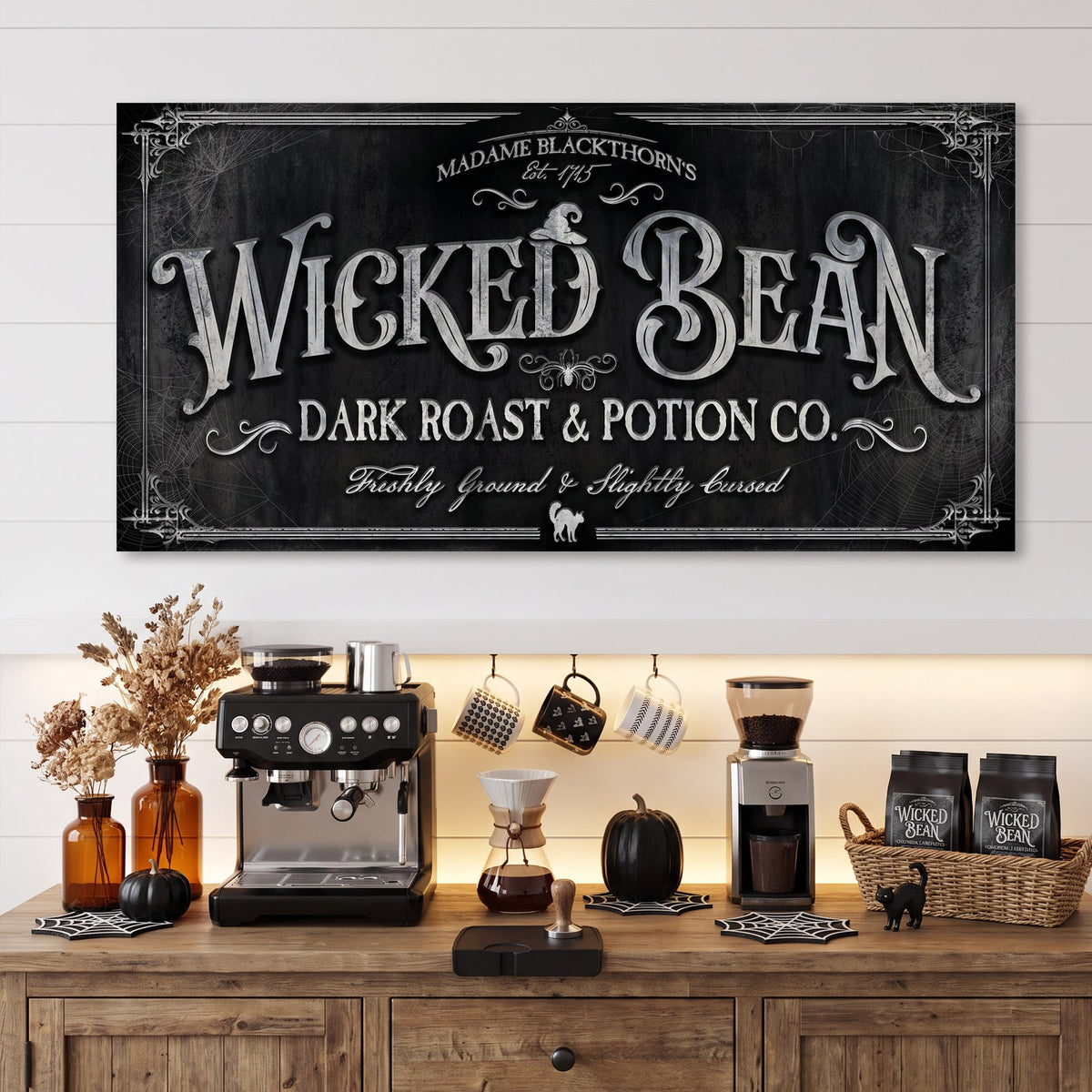Black coffee wall art sign above an espresso machine, grinder and mug rack on a wood sideboard
