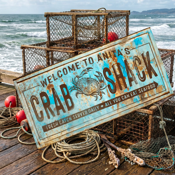 A rustic metal crab sign reading 'Welcome to Anita's Crab Shack' with a blue distressed background and a crab illustration, displayed on a wooden dock with lobster traps, ropes, and the ocean in the background.