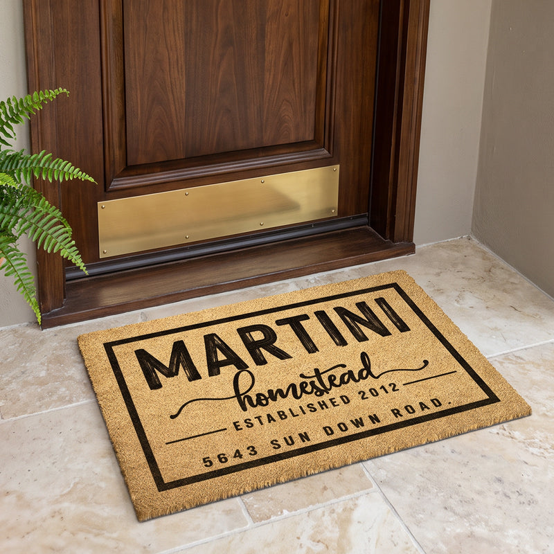 Custom address door mat reading Homestead Established with a street address on a travertine entry