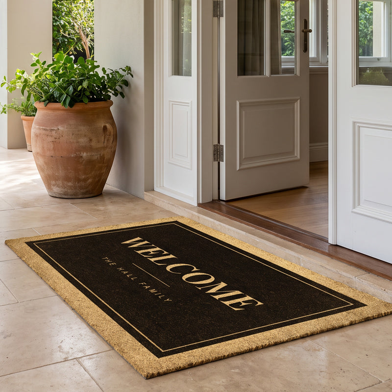 Custom black welcome mat with reversed cream lettering on natural coir at open white french doors