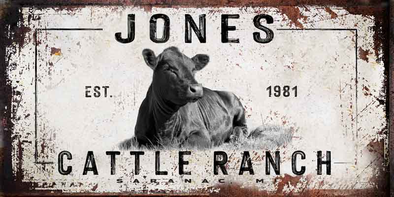 Custom cattle ranch sign with a cow seating in the grass, personalized with name and est. date