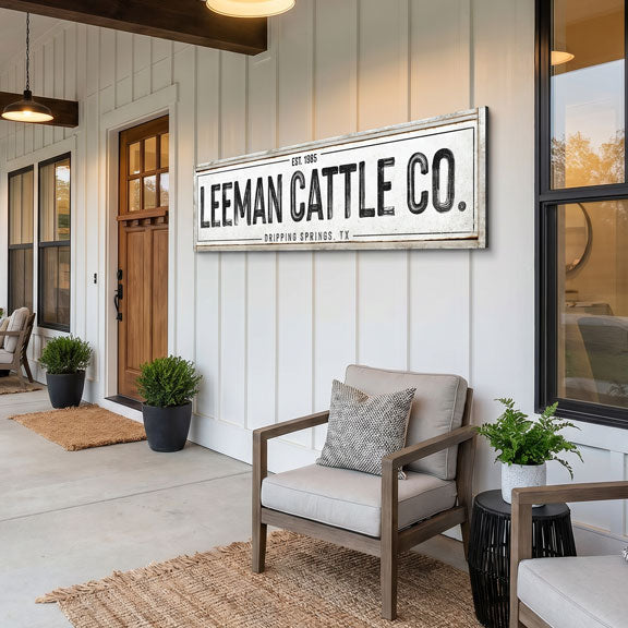Front porch of a house with 'Leeman Cattle Co.' sign above a chair with a custom cattle ranch sign hanging on wall