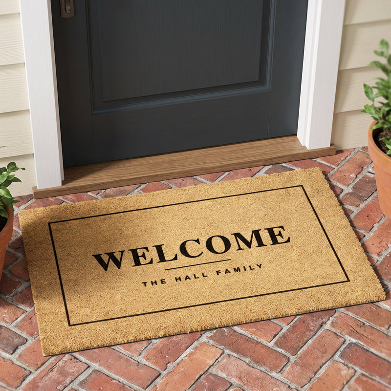 Custom welcome mat with family name at a charcoal door on a herringbone brick porch