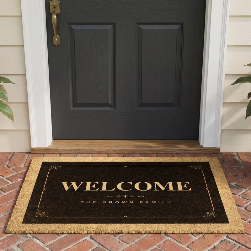 Elegant welcome mat with an ornate gold frame and fleur de lis corners at a black front door