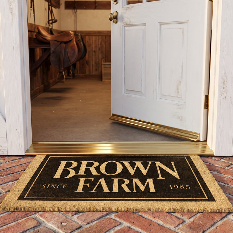 Equine coir door mat at an open stable door with saddles and bridles hanging on the tack room wall