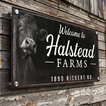 Farm sign with a cow illustration and 'Welcome to Halstead Farms' text on a rustic wooden background.