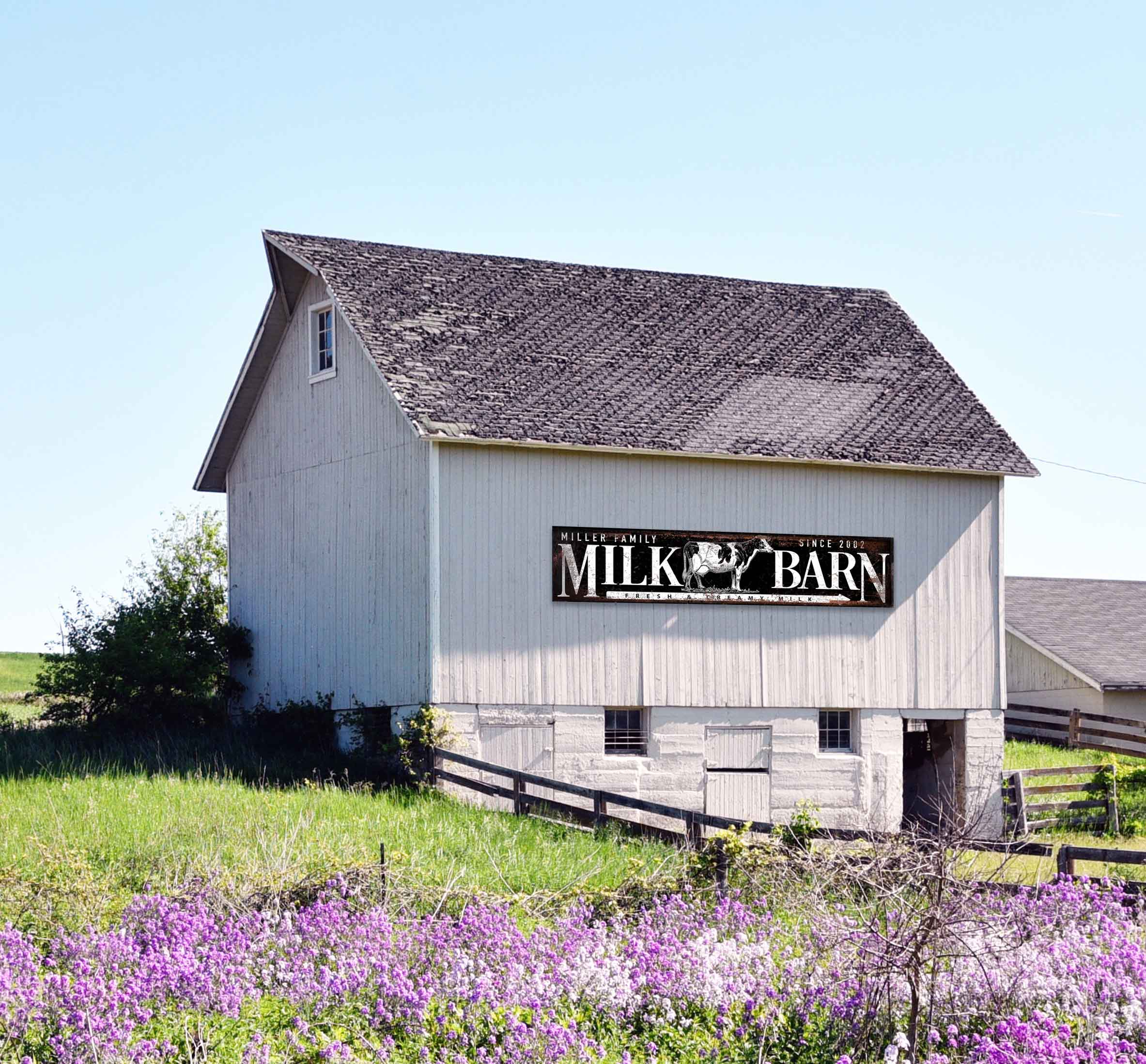 farm sign on the side of a white barn with the words Milk Barn with a cow on a black distressed background