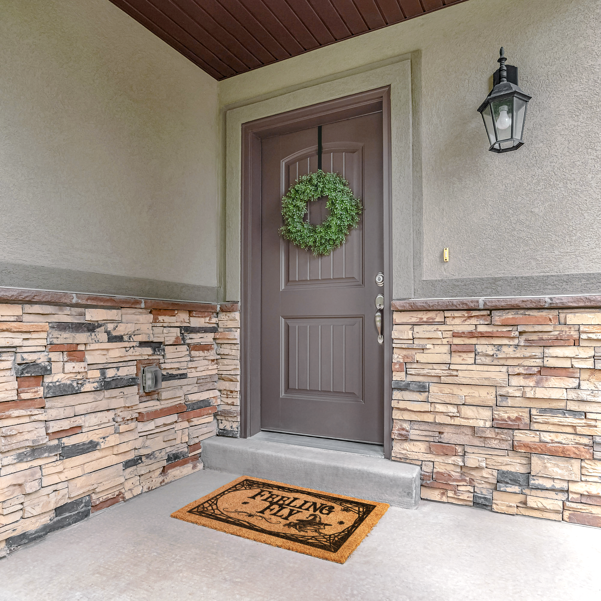 Feeling Fly Halloween doormat on a stone porch below a brown door with a green wreath