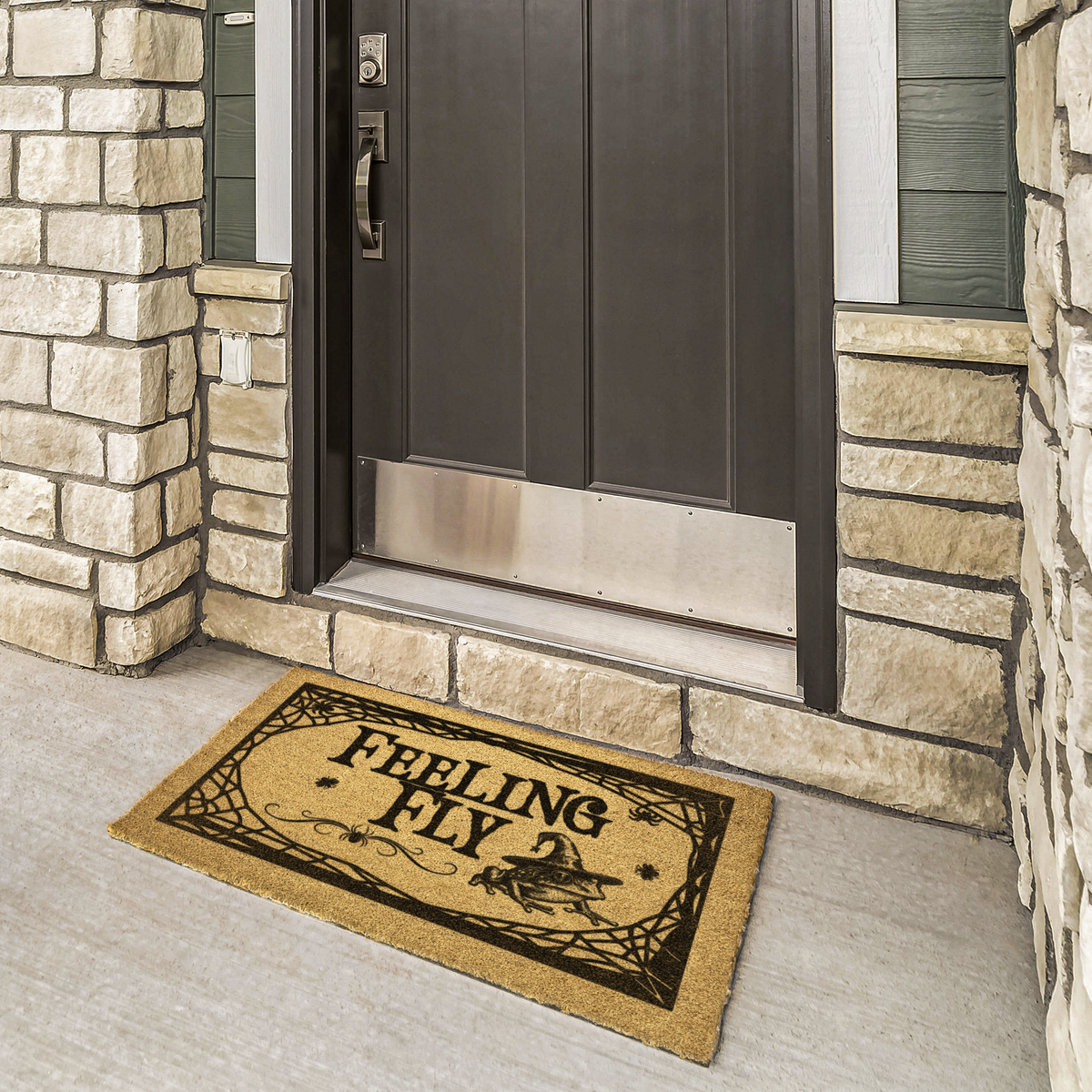Feeling Fly witch doormat in black on natural coir at a bronze front door framed by cream stone