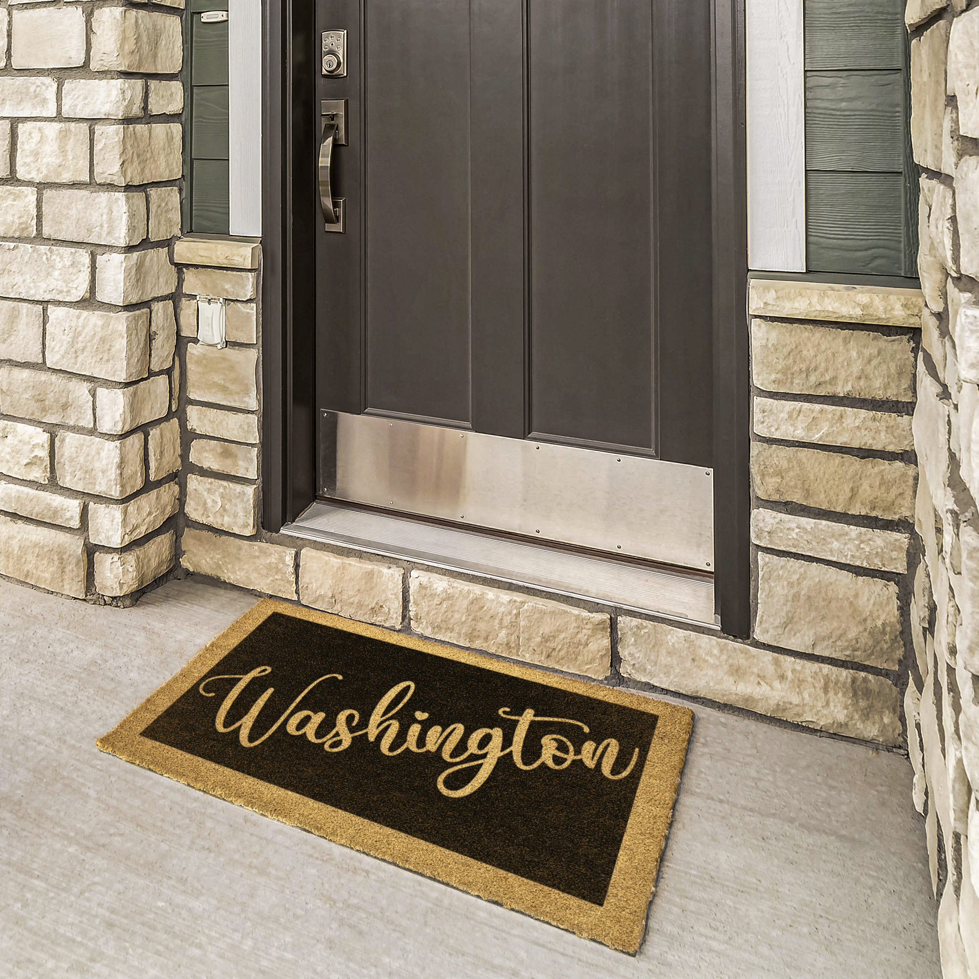 Last name doormat with surname in gold script at a bronze door framed by cream stone
