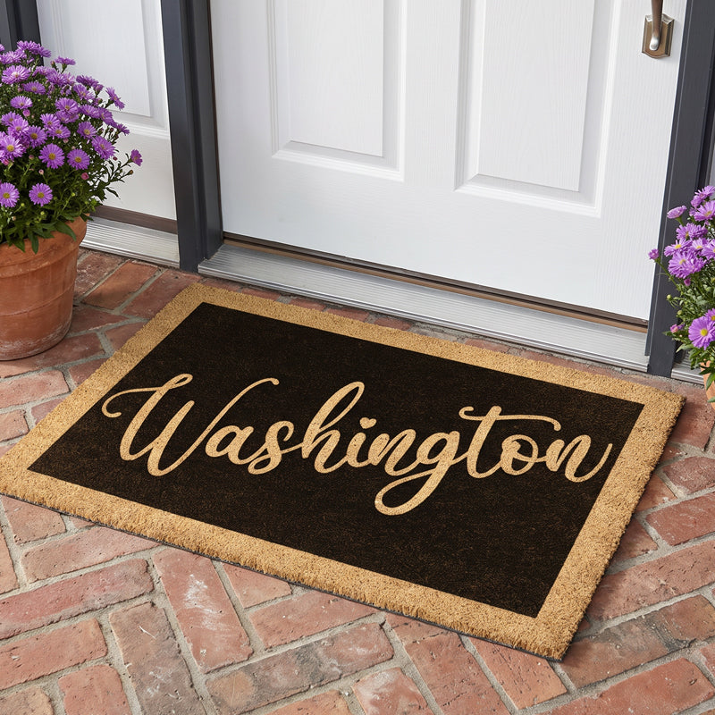 Last name doormat with a surname in gold script on a black field, at a white door with purple asters