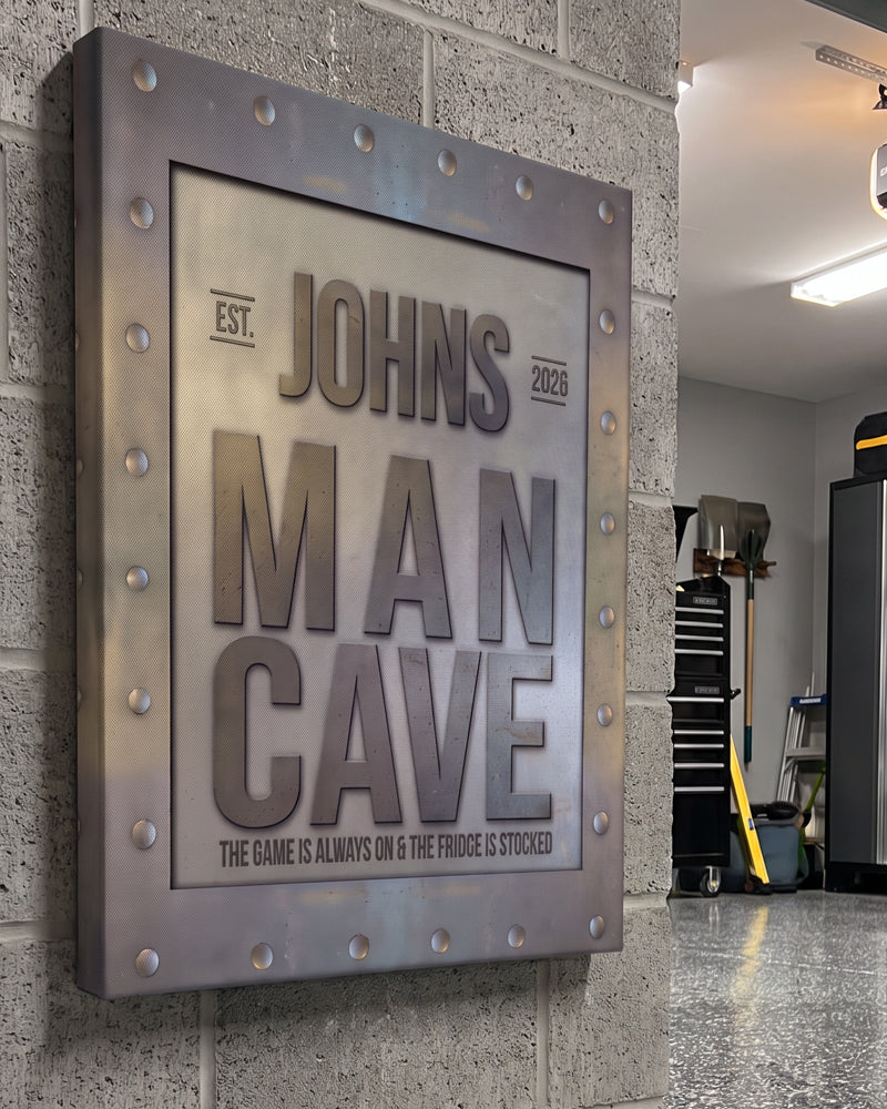 Man cave garage sign on a cinder block wall above tool chests, personalized name and established year
