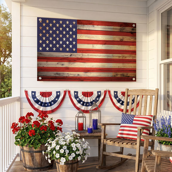 Decorative American flag on a wooden wall with a rocking chair, flowers, and lanterns on a porch.