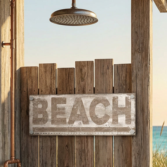 metal beach sign with 'BEACH' on a wooden structure by a window with a view of the ocean.