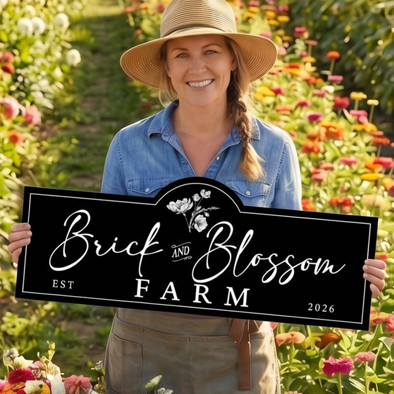 Woman holding a metal farm sign for Brick and Blossom Farm in a garden setting