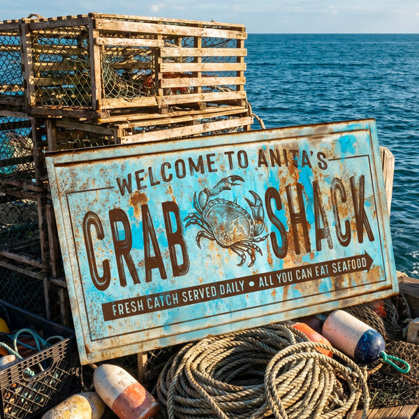 Nautical decor of a weathered blue and brown wooden sign reading 'Welcome to Anita's Crab Shack' with a crab illustration, photographed on a boat deck with lobster traps, ropes, buoys, and the ocean in the background.