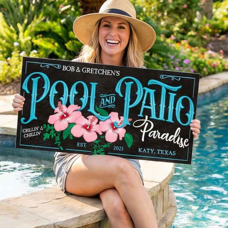 Woman holding outdoor pool decor sign by a pool with floral designs and text.