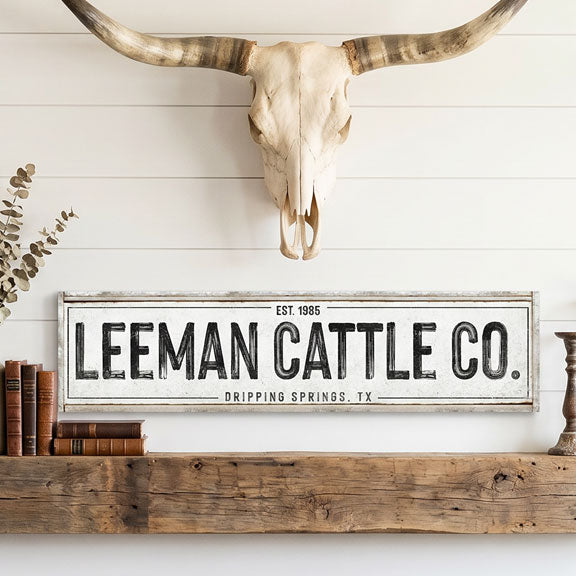 Personalized cattle ranch sign Leeman Cattle Co. sign on a wall with a bull skull and books.