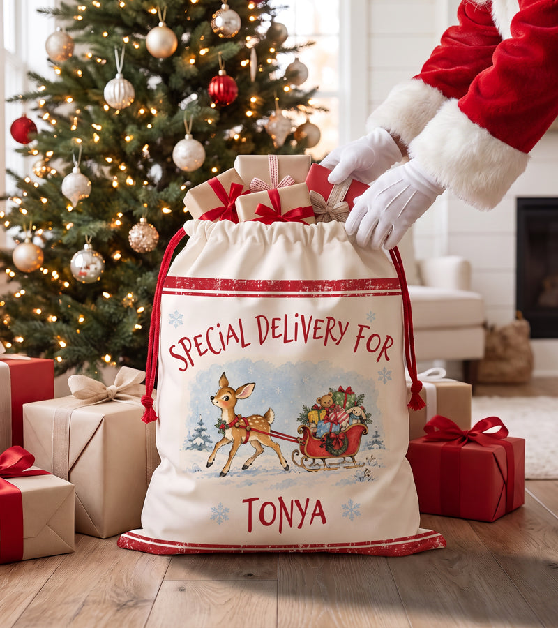 Personalized Christmas gift bag for a baby, watercolour fawn and sleigh design, filled with presents beside a fireplace