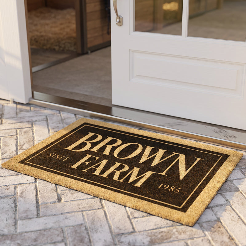 Personalized farm mat with farm name and year on coir, at a white glass door with stable bedding beyond