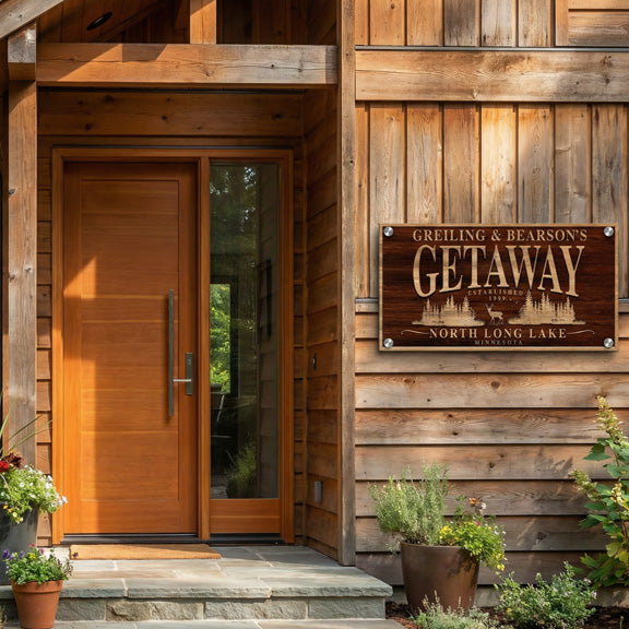 Personalized lake house sign on a cedar cabin wall by the front door with potted plants in the sun