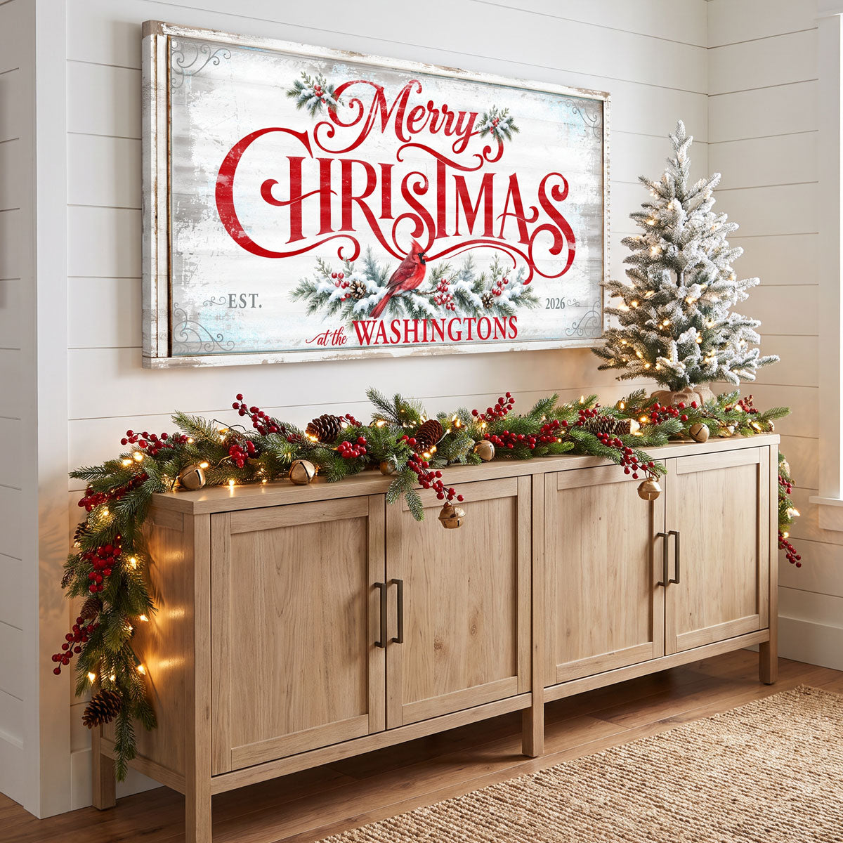 Personalized Merry Christmas sign above an oak sideboard with a lit garland, red berries and brass bells
