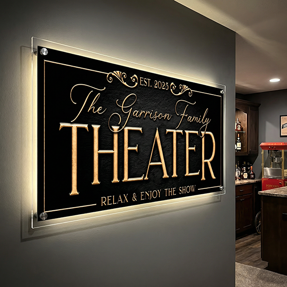 Decorative personalized theater room sign for 'The Garrison Family Theater' with gold text on a black background, mounted on a wall.